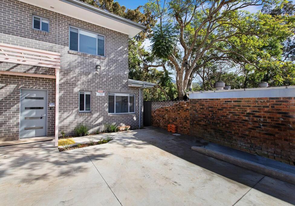 a brick house with a garage and a brick wall at Sip and Dip - Woonona in Woonona