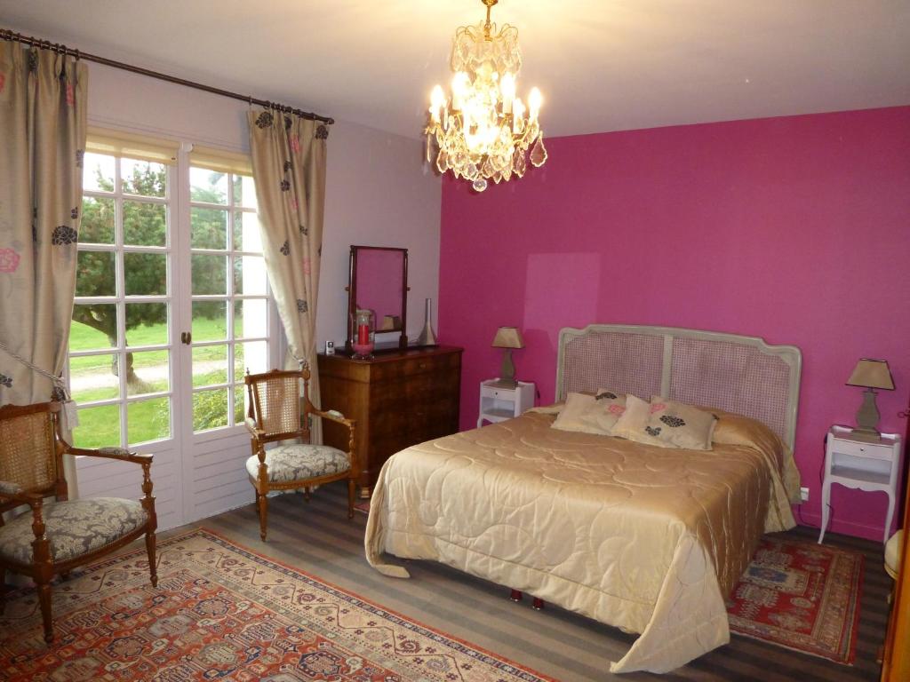 ein lila Schlafzimmer mit einem Bett und einem Kronleuchter in der Unterkunft Le Clos du Pont Martin in Saint-Briac-sur-Mer