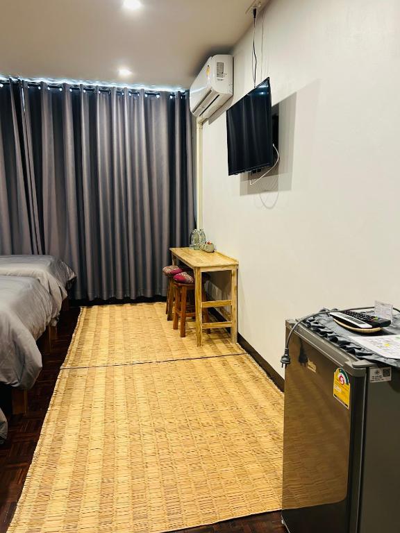 a room with a bed and a table and a television at Chern Chiangmai Boutique Hotel in Chiang Mai