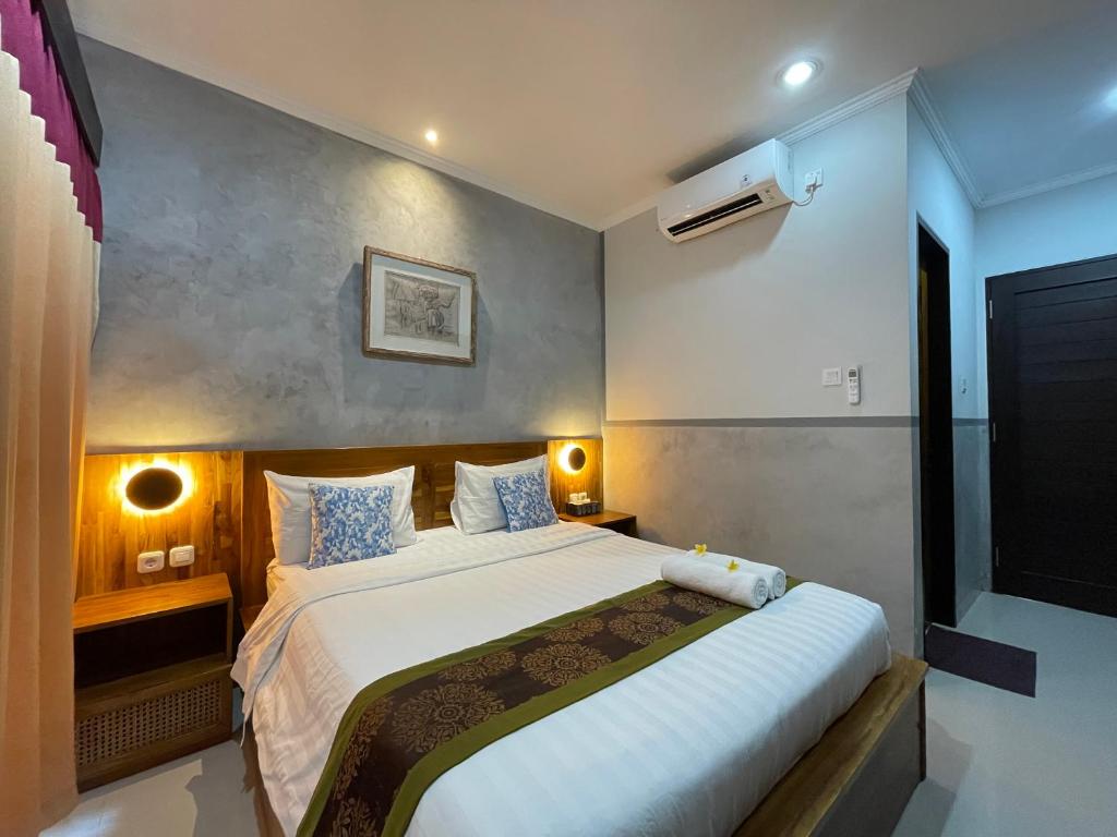 sypialnia z dużym białym łóżkiem i niebieskimi poduszkami w obiekcie Kubu Indah Homestay Sanur w mieście Sanur