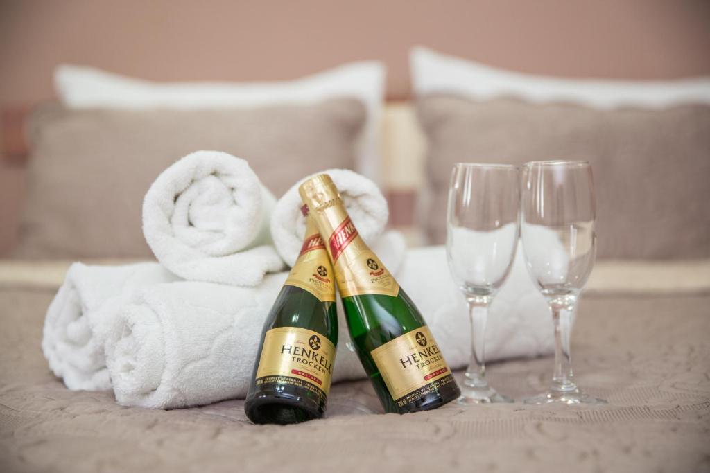twee champagneflessen op een tafel met handdoeken en wijnglazen bij Sin-Kom Hotel Garni in Pirot