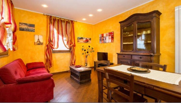アオスタにあるWallace Apartmentの黄色の壁のリビングルーム(赤いソファ付)