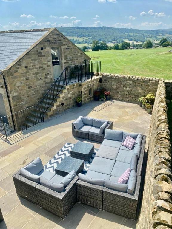 a patio with two couches and a stone building at Kiln House Lodge in Harrogate