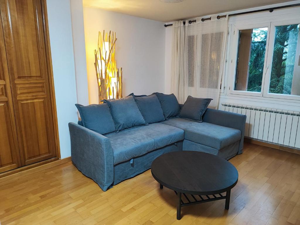 a living room with a blue couch and a table at Cette Maison est la Vôtre in Suresnes