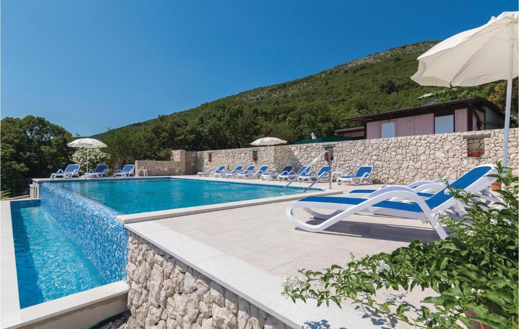 basen z krzesłami i parasolami obok budynku w obiekcie 3 Bedroom Cozy Apartment In Labin w mieście Ravni