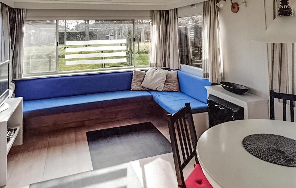 ein Wohnzimmer mit einem blauen Sofa vor einem Fenster in der Unterkunft Gorgeous Stacaravan In Tzummarum in Tzummarum