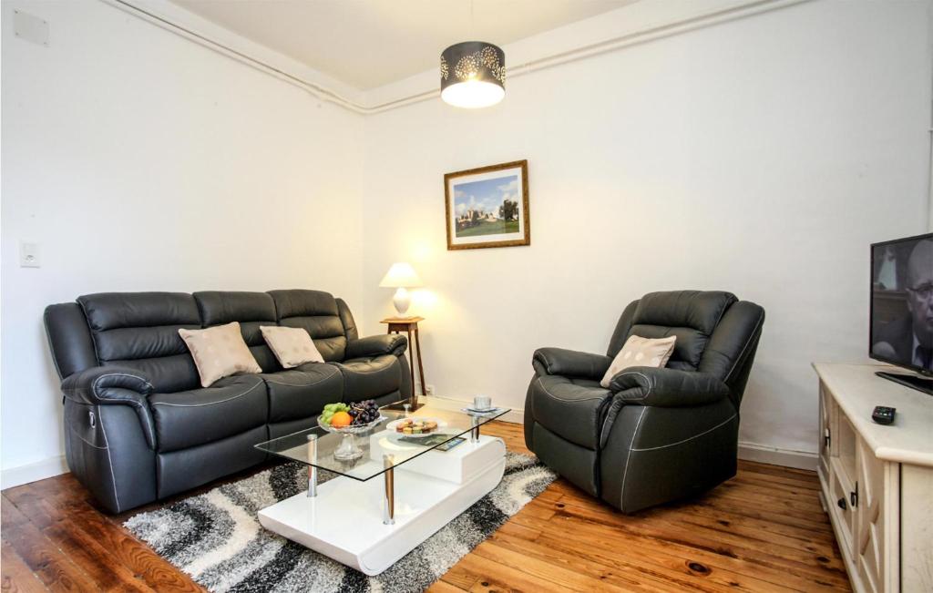 a living room with two black couches and a tv at St Marie in Sarlat-la-Canéda