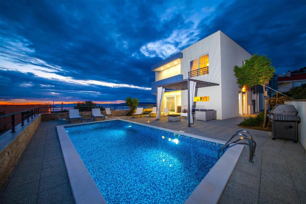 a villa with a swimming pool in front of a house at Villa Red with pool and sea view in Makarska