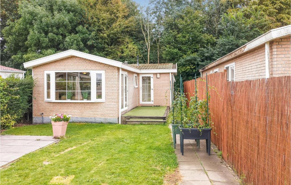a small house with a fence in a yard at Nice Home In Heinkenszand With Wifi in Heinkensand