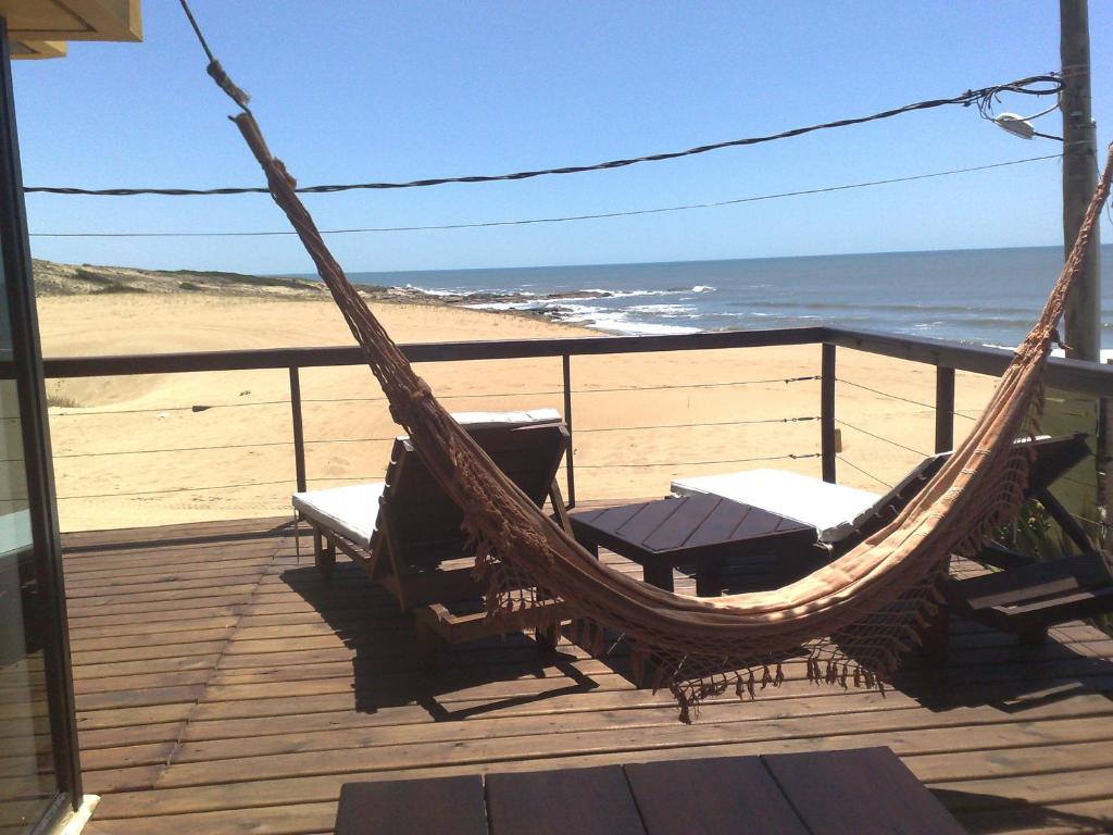 a hammock on a deck with a view of the beach at Lobos de Mar in Punta Del Diablo