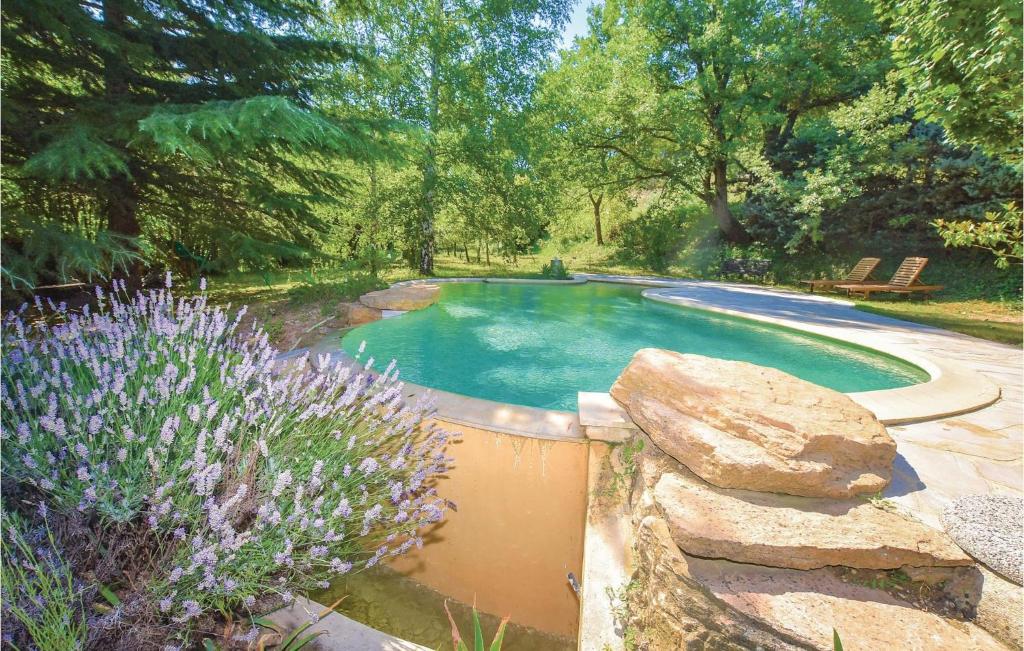 une piscine dans un jardin avec des fleurs violettes dans l'établissement Lovely Home In Malaucene, à Malaucène