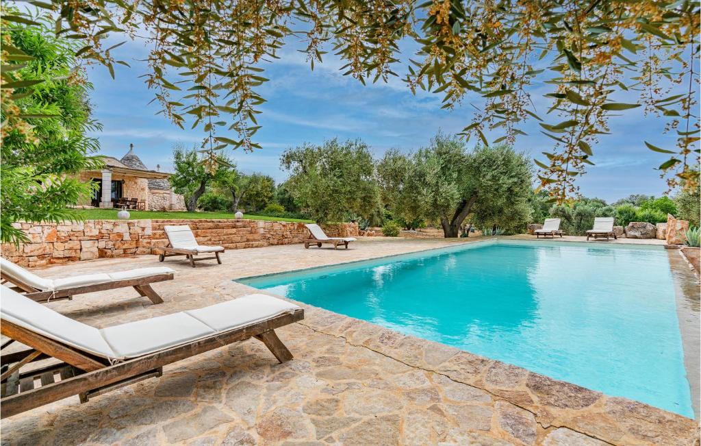 a swimming pool with two chaise lounges next to a stone wall at Beautiful Home In Ostuni -Br- in Ostuni
