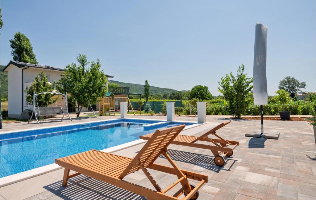 a swimming pool with two lounge chairs next to a pool at Lovely Home In Donji Prolozac With Wifi in Donji Proložac