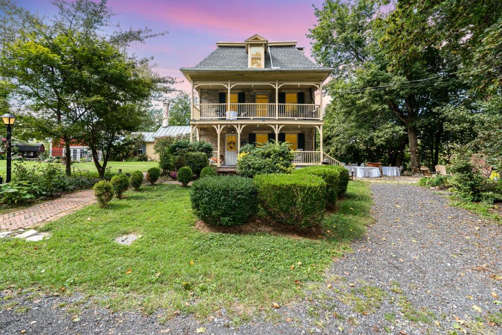 an old house with a porch and bushes at Fallen Tree Farm Bed and Breakfast in Carlisle