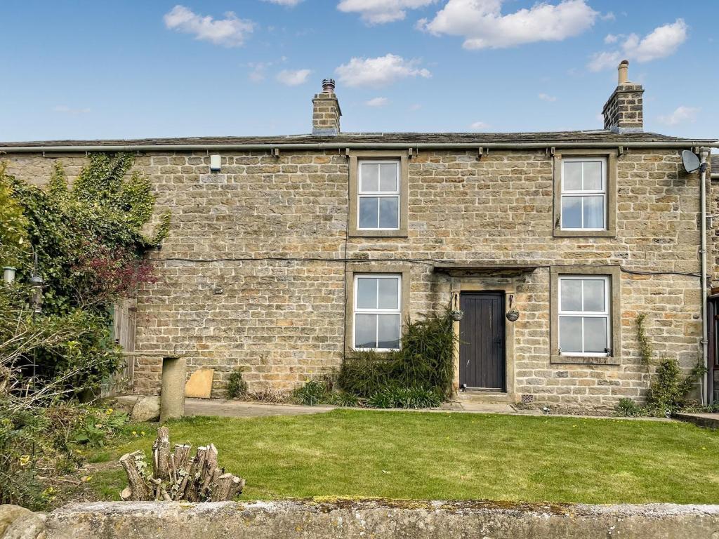 an old brick house with a lawn in front of it at Bondcroft Farm Cottage in Embsay