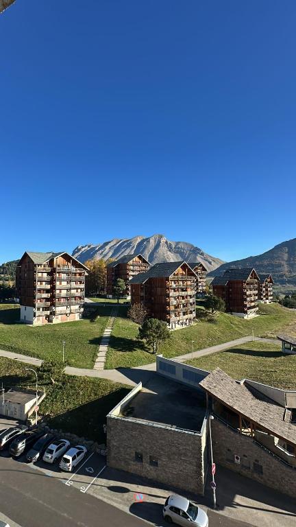 un groupe de bâtiments avec des voitures garées dans un parking dans l'établissement Studio 4 à 6 personnes, à Saint-Étienne-en-Dévoluy