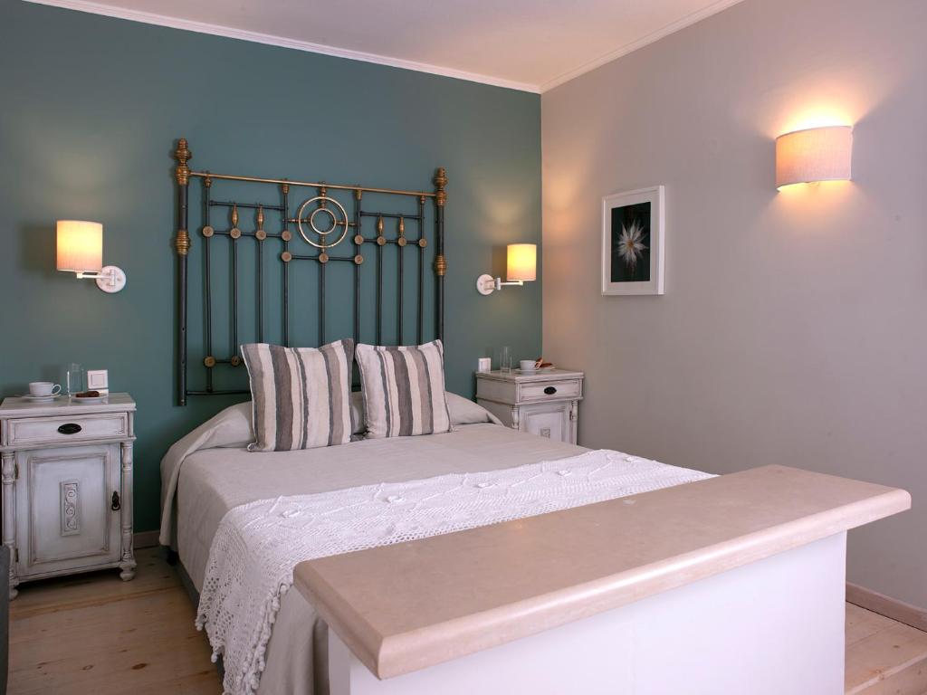 a bedroom with a bed with a green headboard and two tables at Mythos Suites Boutique Hotel in Rethymno