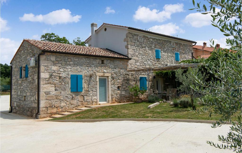 kamienny dom z niebieskimi okiennicami i podjazdem w obiekcie 3 Bedroom Amazing Home In Ruzici w mieście Ružići