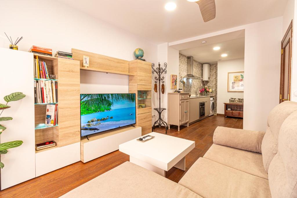 a living room with a couch and a tv at La petite maison de Nadette in Gandía