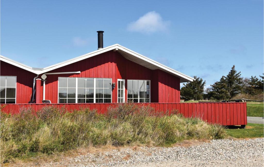 un granero rojo con una valla roja delante en Holiday Home Anker Eskildsensvej Hvide Sande Vi, en Nørre Lyngvig