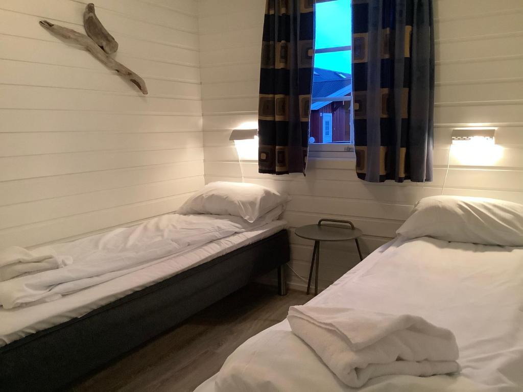 two twin beds in a room with a window at Ytterviks Rorbu Lofoten Welcome 欢迎 in Stamsund