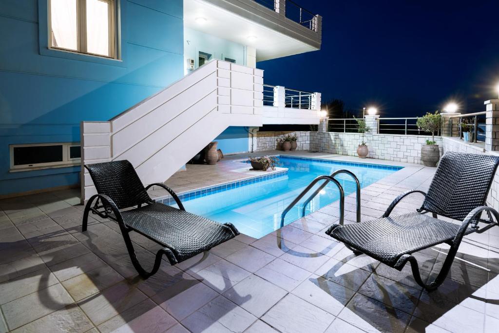 a pool with two chairs and a staircase next to a house at Kronos Villas in Kolymvari