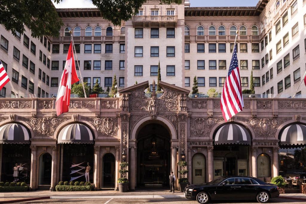 un'auto parcheggiata di fronte a un edificio con bandiere di Beverly Wilshire, A Four Seasons Hotel a Los Angeles