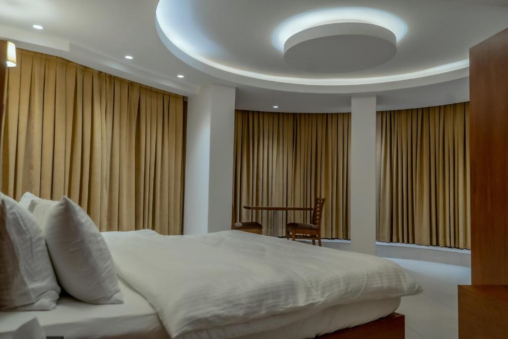 a bedroom with a large white bed and windows at Coral Karbala Hotel in Karbala