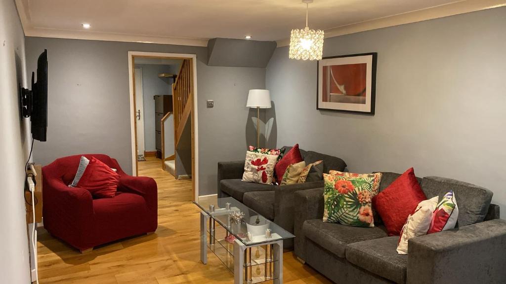 a living room with two couches and a red chair at Warm and Homely 4 Bed house w big Garden & Parking in Milton