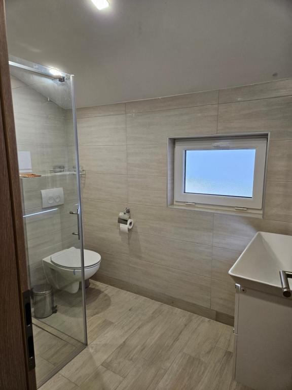a bathroom with a shower and a toilet and a window at Apartment Anton in Selce
