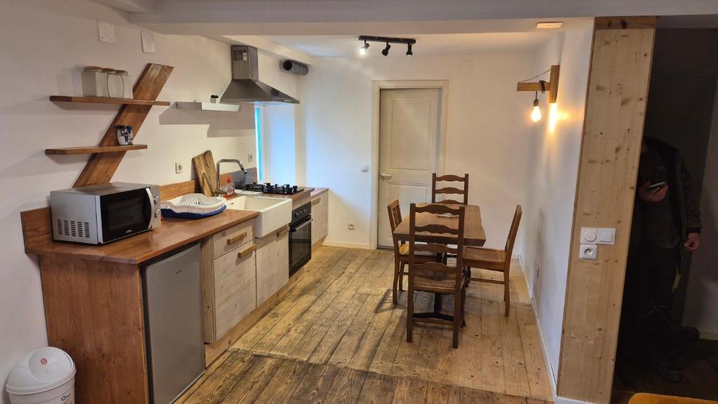 Il comprend une cuisine équipée d'un four micro-ondes et d'une table avec des chaises. dans l'établissement 2 pièces sud, à Wasselonne