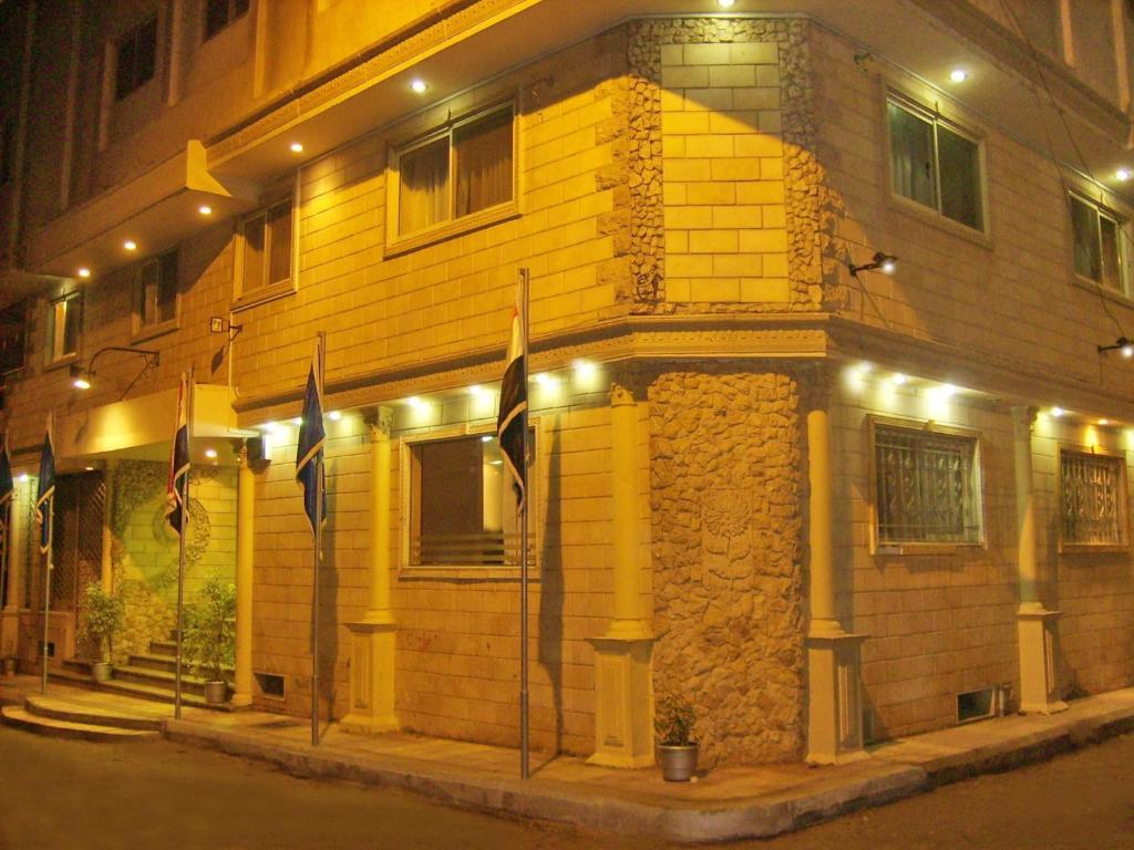 um edifício amarelo com bandeiras à frente à noite em Alexandria Mediterranean Suites em Alexandria