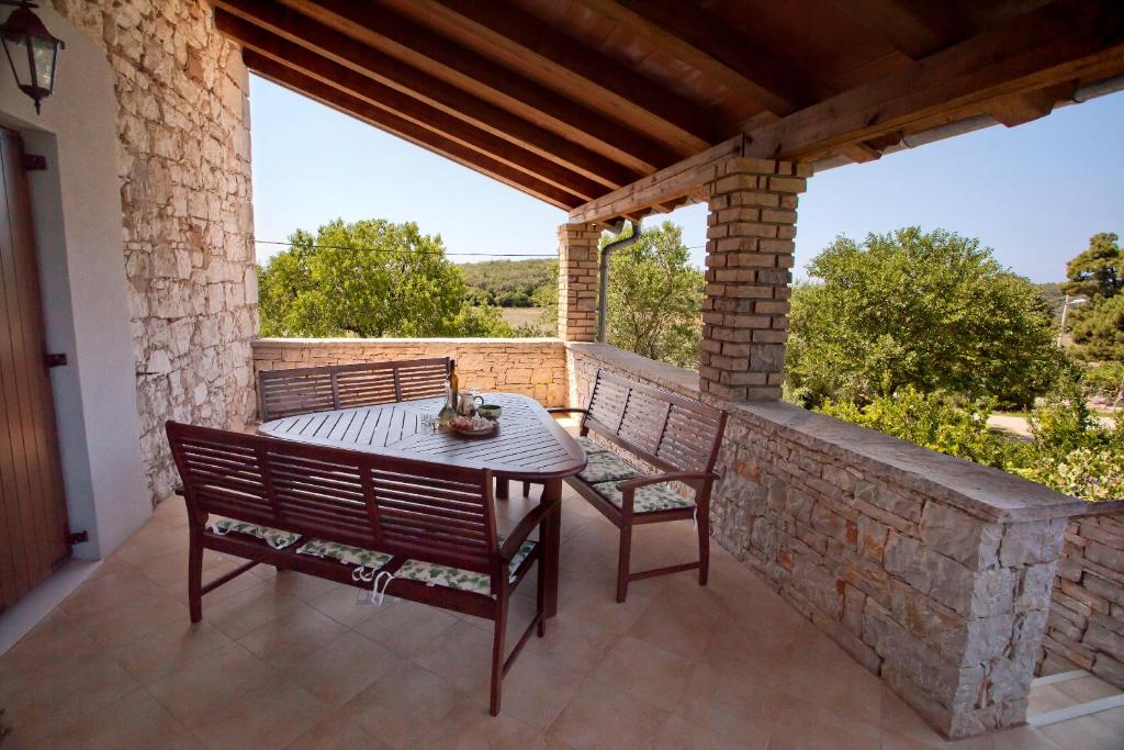 a patio with two chairs and a table on a stone wall at Holiday Home Stancija Becic in Mugeba
