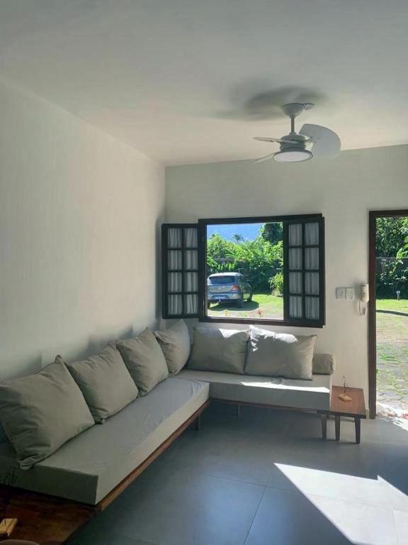 a couch in a living room with a window at Cana Caiana Casa in Paraty