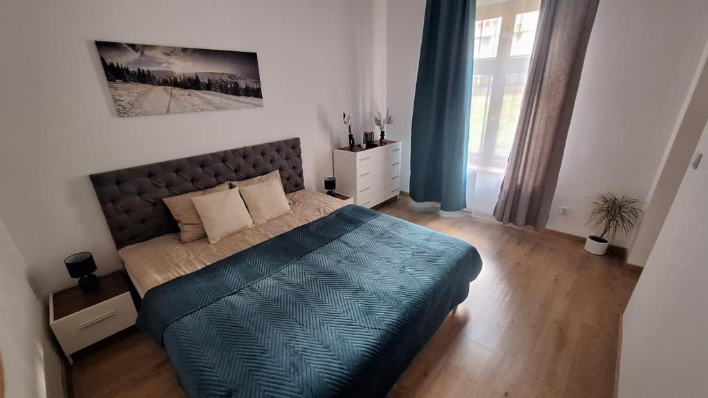 a bedroom with a bed with a blue comforter at Apartamenty Droga na Śnieżkę in Karpacz