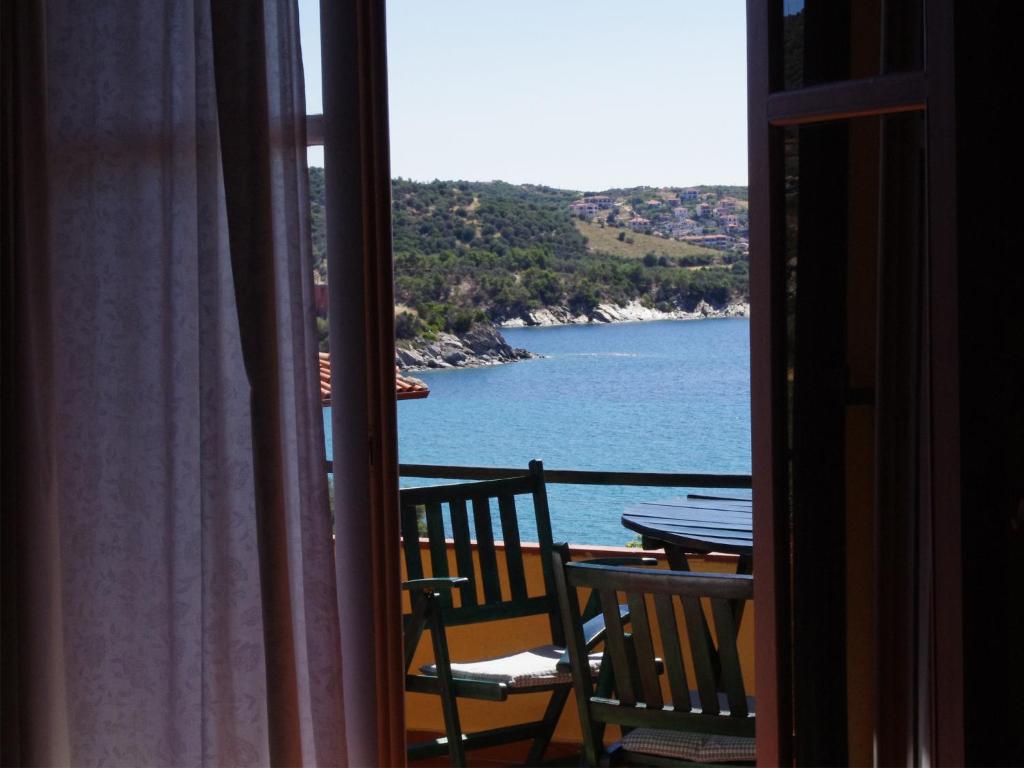 a room with a view of the ocean from a balcony at The Yellow Houses in Ayios Nikolaos Sithonia