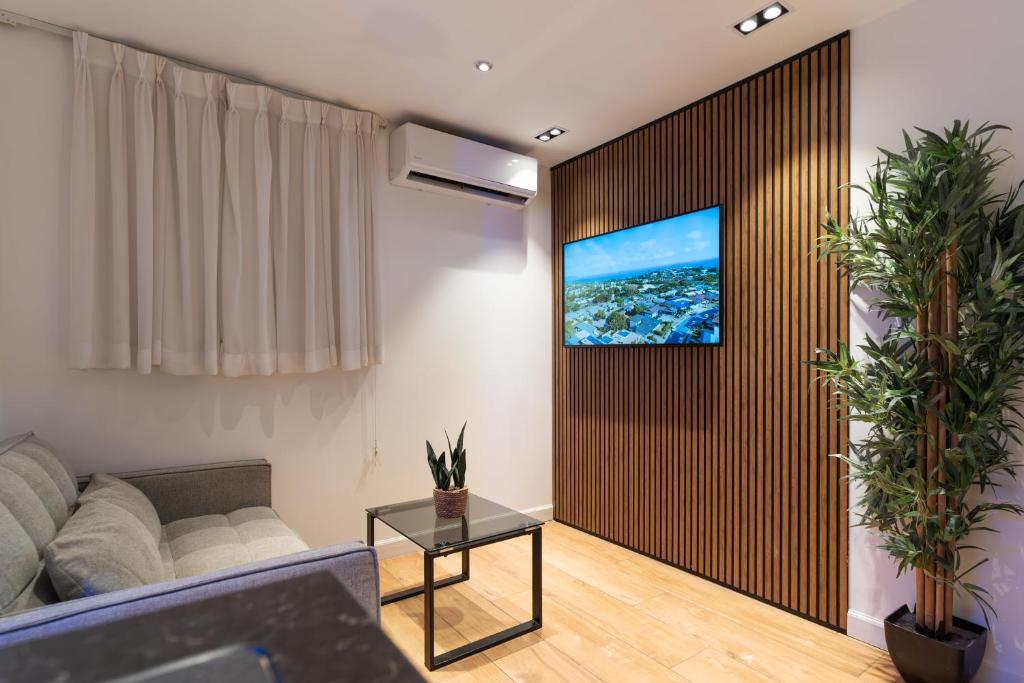 ein Wohnzimmer mit einem Sofa und einem Fernseher an der Wand in der Unterkunft סוויטות אוראל 432 in Eilat