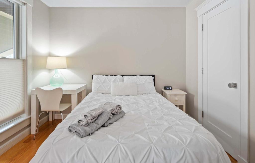 a white bedroom with a bed and a desk and a window at Inviting 3BR In Cambridge Walk To T & Central Sq in Cambridge