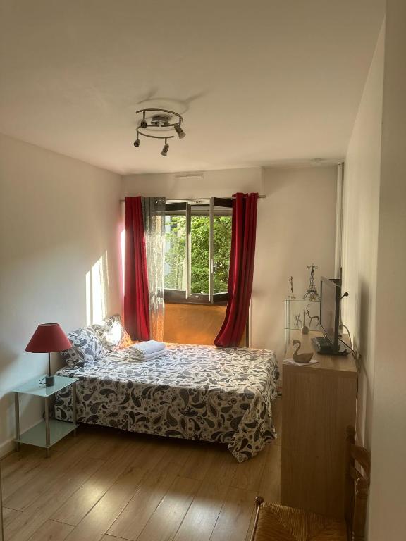 une chambre avec un lit et une fenêtre avec des rideaux rouges dans l'établissement Calm and Comfortable parisian studio, à Paris