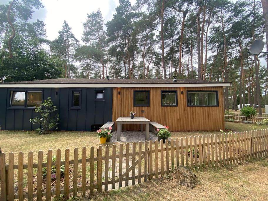 une petite maison dans une cour avec une clôture dans l'établissement Luxe groot chalet voor 6 personen op de Veluwe!, à Doornspijk