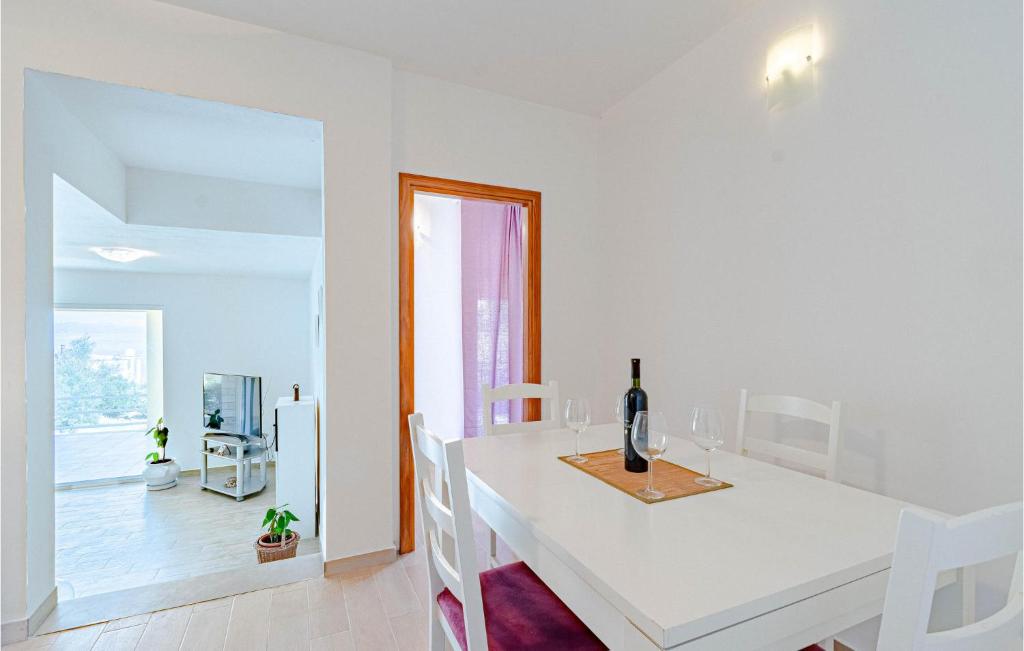 biała jadalnia z białym stołem i butelką wina w obiekcie Amazing Home In Blato w mieście Blato