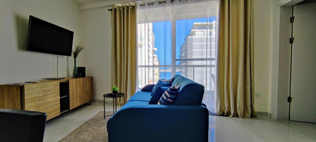 a living room with a blue couch and a large window at Seaview Three-O-Two in St. Paul's Bay