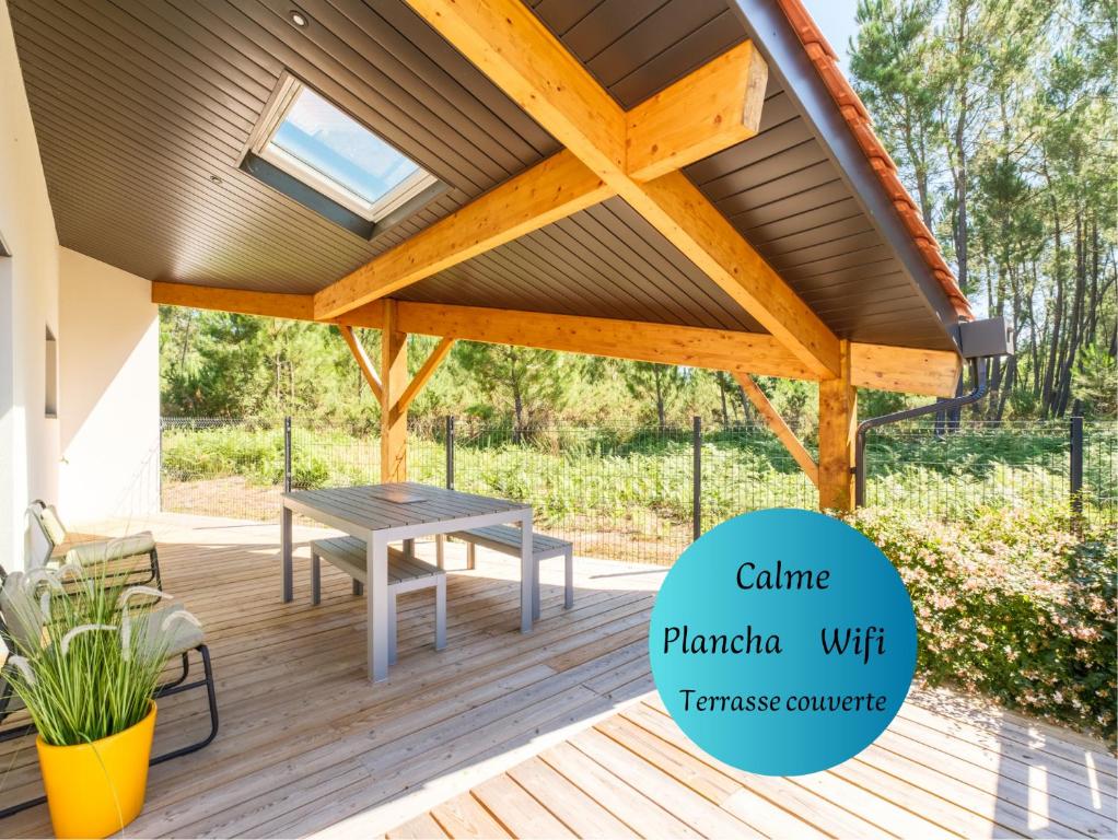 une pergola en bois avec une table de pique-nique sur une terrasse dans l'établissement Maisonnette de charme au calme, à Pontenx-les-Forges