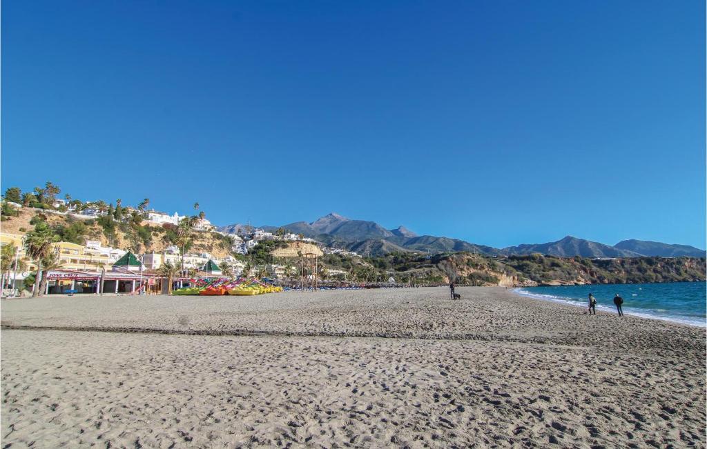 a beach with people walking on the sand and the water at Beautiful Home In Nerja With Wifi in Nerja