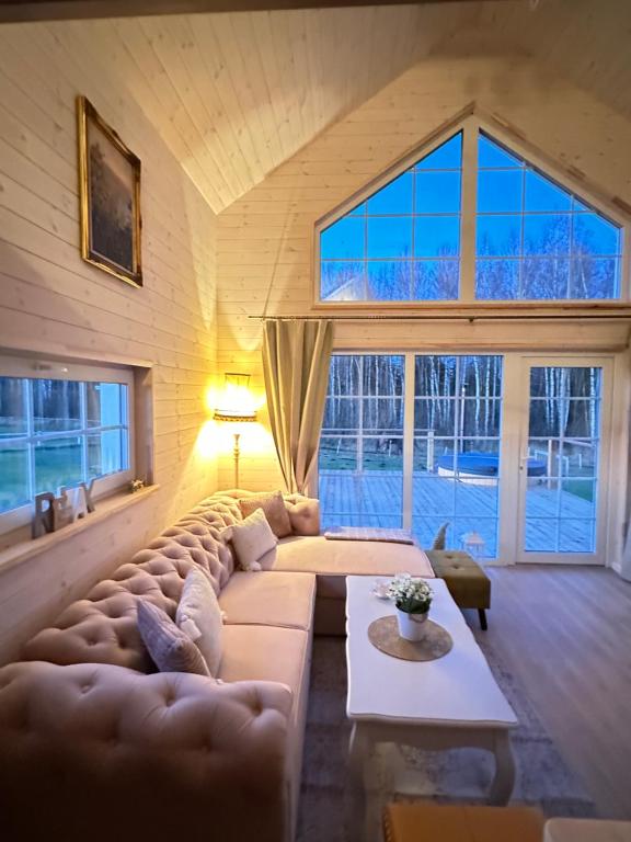 a large living room with a large couch and windows at Relax House By The Stone in Nugariai