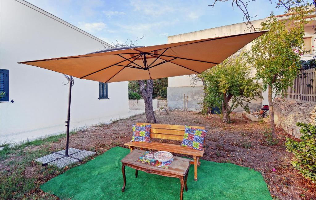 drewniana ławka siedząca pod dużym parasolem w obiekcie Nice Home In Cava Daliga With Wifi w mieście Cava dʼAliga