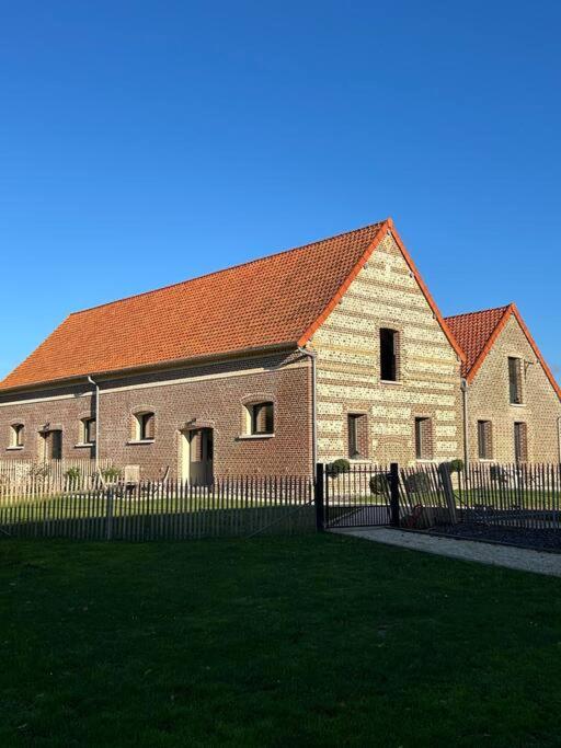 un grand bâtiment en briques avec une clôture devant dans l'établissement Gites les Amourettes, à Saint-Aubin-sur-Scie