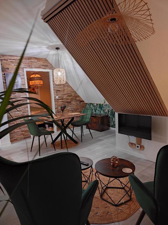 een woonkamer met stoelen, een tafel en een tv bij L'Obernai in Obernai