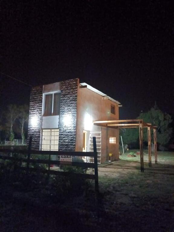 a small house at night with a fence in front of it at El Campito in Necochea