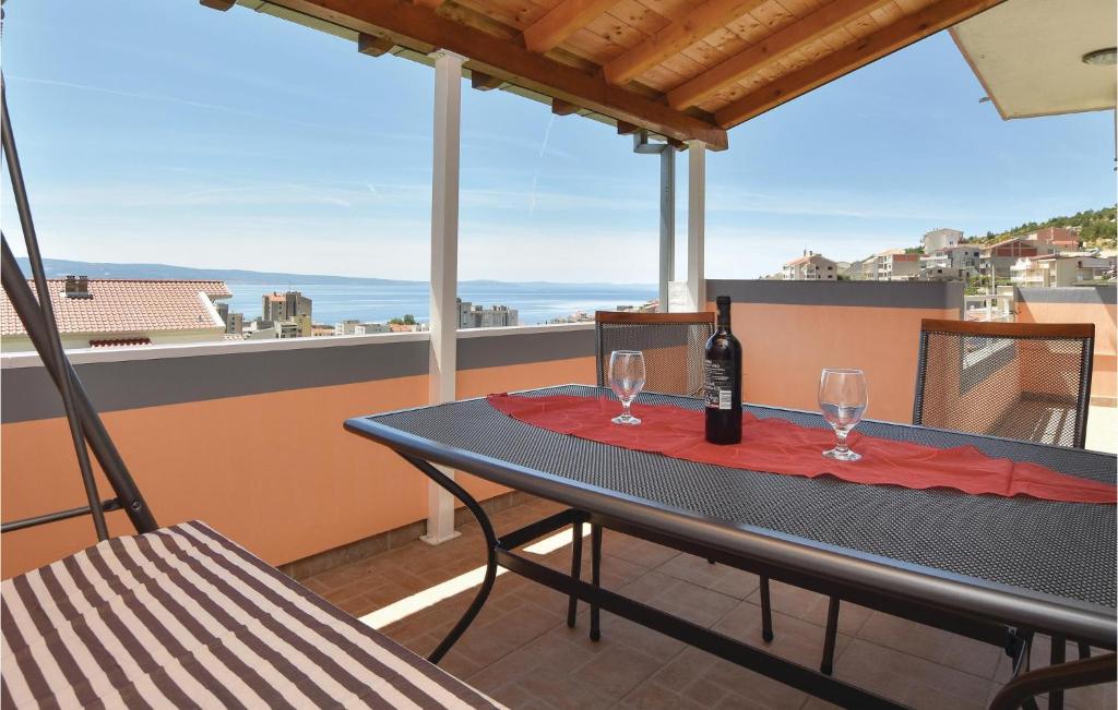 een tafel met een fles wijn en glazen op een balkon bij One-Bedroom Apartment Dugi Rat With Sea View 06 in Dugi Rat